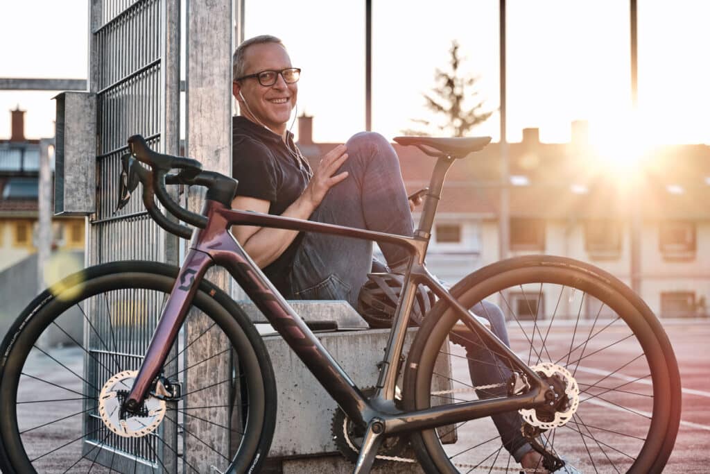 Happy man sitting on a bench next to his bike.